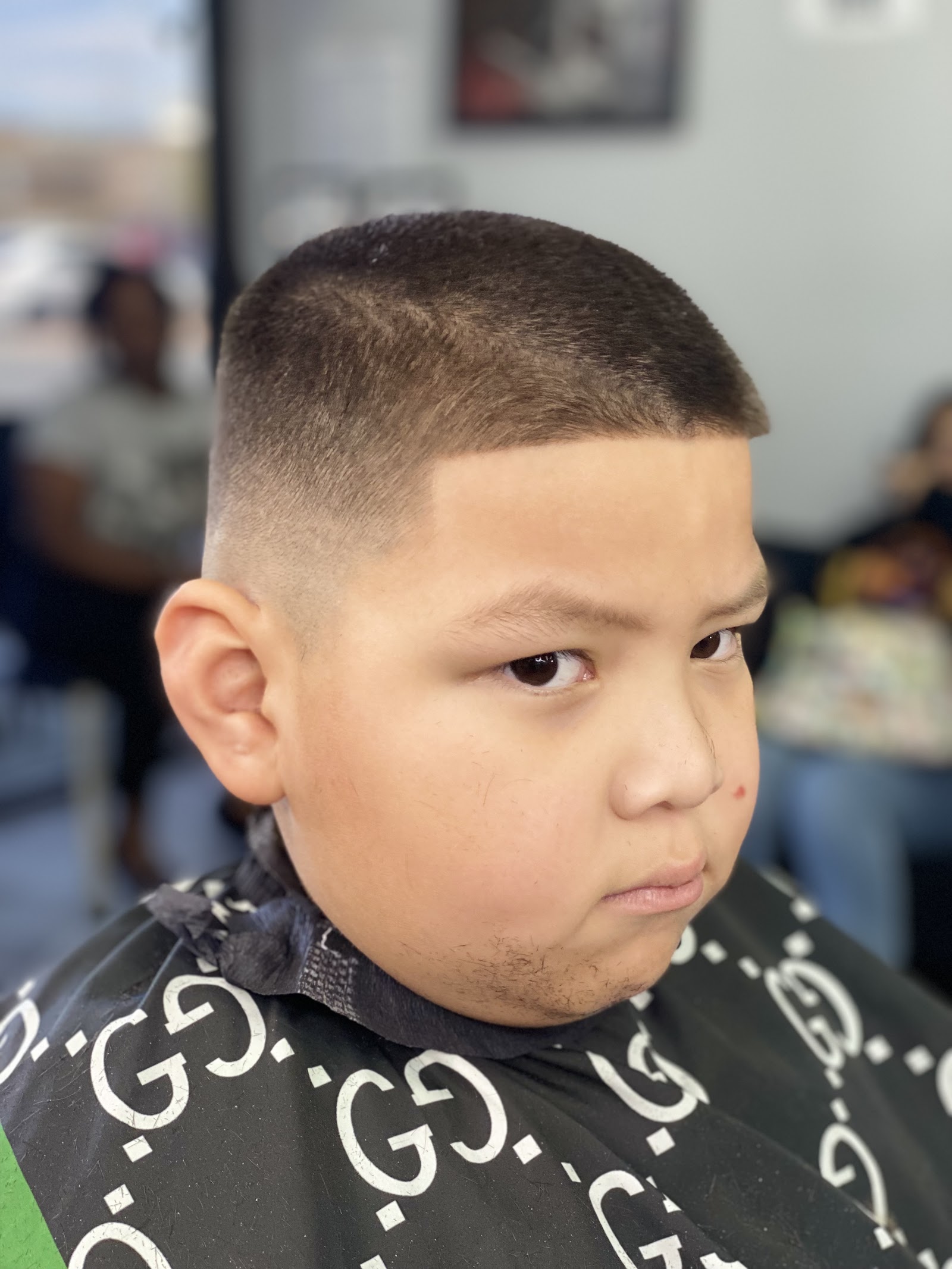 Young boy with a clean crew cut and line-up fade wearing a barber cape