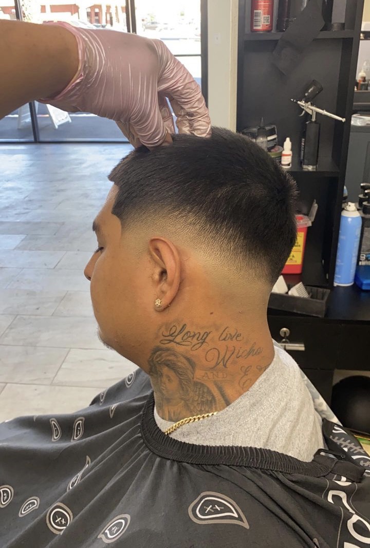 Back view of a man's fresh taper fade with a neck tattoo during the cut