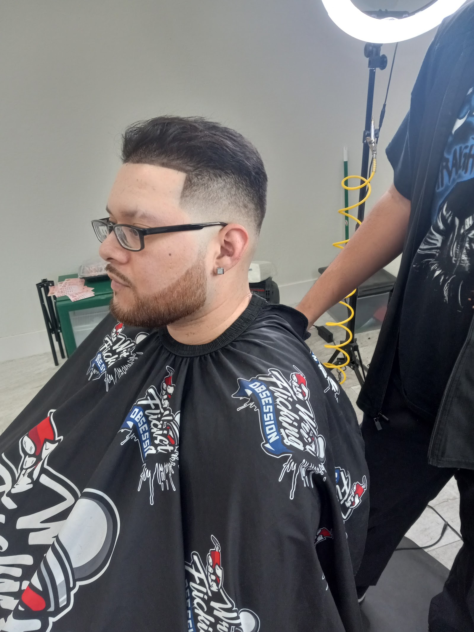 Man with a fresh taper fade haircut wearing a barber cape in the shop