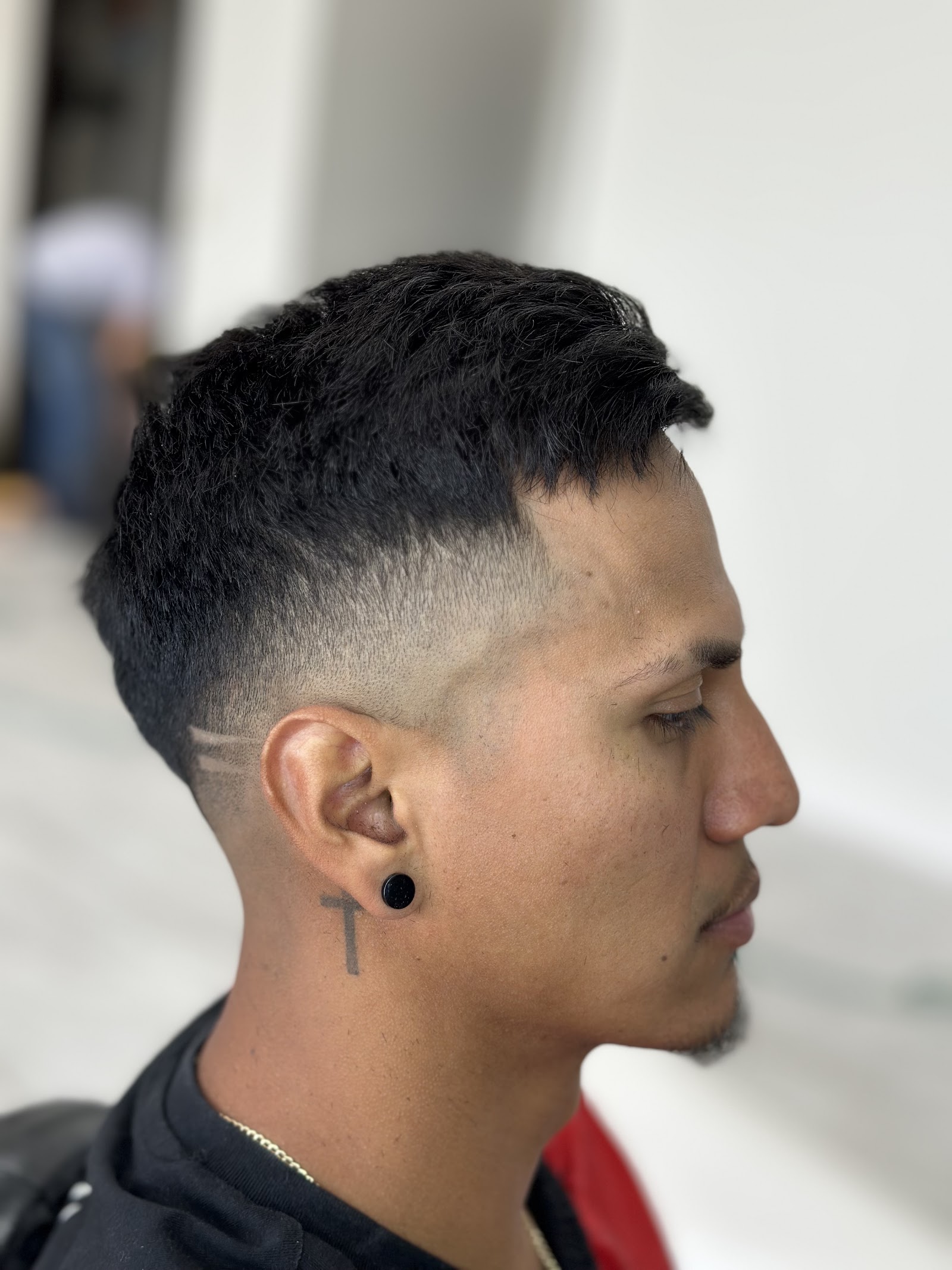 Side profile of a man with a textured crop and high skin fade finished with a crisp design line